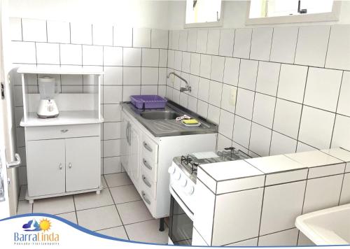 a white tiled kitchen with a sink and a stove at Pousada Barra Linda in Florianópolis