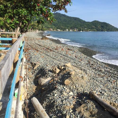 a rocky beach with a blue fence and the ocean at Cabañas Tucan Eco Hotel in Capurganá