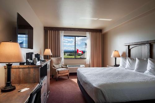 a hotel room with a bed and a desk and a window at Glacier International Lodge in Kalispell