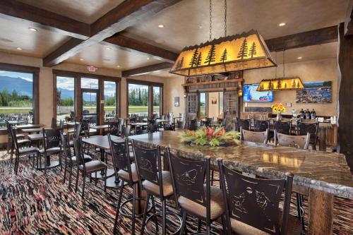 a restaurant with a large bar and tables and chairs at Glacier International Lodge in Kalispell