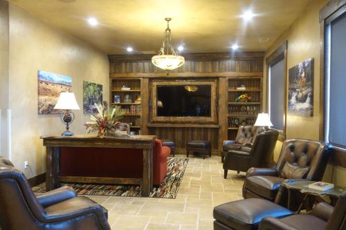 a living room with a fireplace and chairs and a tv at Glacier International Lodge in Kalispell