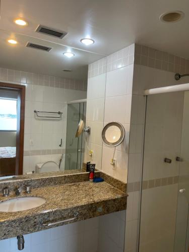 a bathroom with a sink and a mirror and a shower at Flat Tropical in Manaus