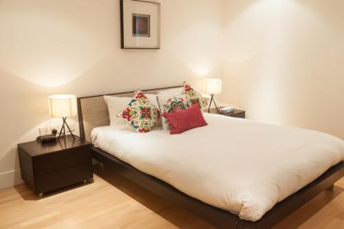 een slaapkamer met een bed met kussens en 2 lampen bij Modern Apartment in Central London By River Thames in Londen