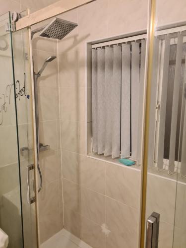 ein Bad mit einer Dusche und einer Glastür in der Unterkunft L & J ESCAPES- 4 BEDROOMs SUITABLE FOR CONTRACTORS AND FAMILIES- LARGE PRIVATE PARKING-10 MINUTES TO M6 JUNCTION 9 in Coseley