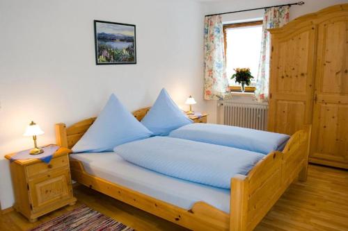 ein Schlafzimmer mit einem großen Holzbett mit blauen Kissen in der Unterkunft Ferienwohnungen am Westernberg in Ruhpolding