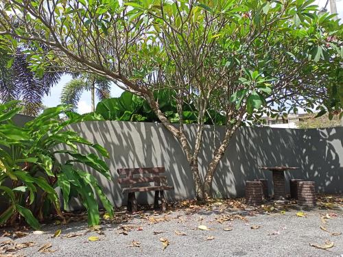a bench and a tree next to a fence at Ipoh Comfortable Rooms Only-Private Bathrooms Indoor Car Parking SY30 in Ipoh