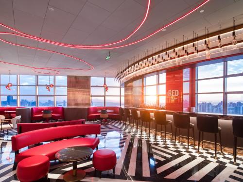 a lobby with red chairs and tables in a building at Radisson RED Hotel Zhuhai Gongbei Port in Zhuhai