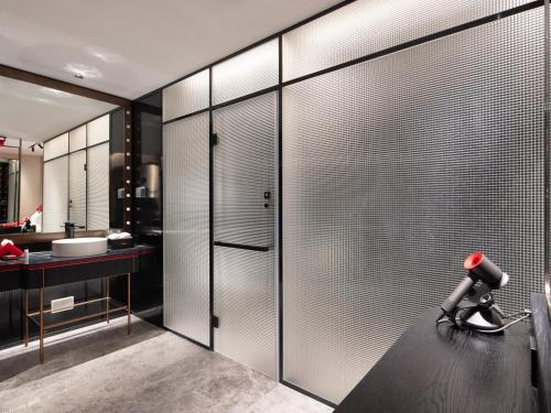 a bathroom with sliding glass doors and a camera on a counter at Radisson RED Hotel Zhuhai Gongbei Port in Zhuhai