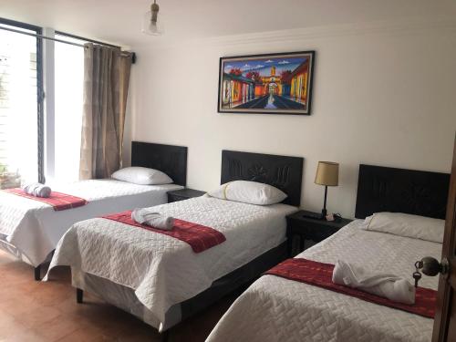 a room with three beds and a painting on the wall at Hotel Mansion Del Rey in Antigua Guatemala