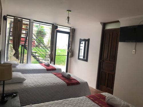 a room with two beds and a television and a window at Hotel Mansion Del Rey in Antigua Guatemala