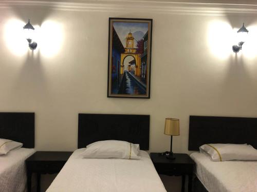 a room with two beds and a picture on the wall at Hotel Mansion Del Rey in Antigua Guatemala