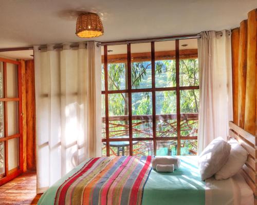 1 dormitorio con cama y ventana grande en Eco Quechua Lodge en Santa Teresa