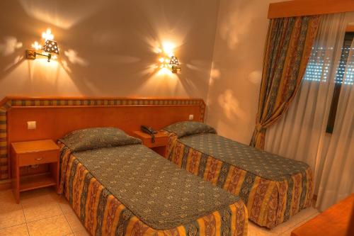 a hotel room with two beds and a window at Real Caparica Hotel in Costa da Caparica