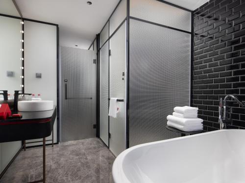 a bathroom with a tub and a shower and a sink at Radisson RED Hotel Zhuhai Gongbei Port in Zhuhai