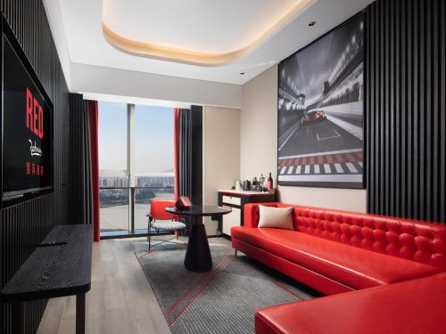 a living room with a red couch and a table at Radisson RED Hotel Zhuhai Gongbei Port in Zhuhai