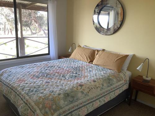 a bedroom with a bed and a mirror on the wall at Gilgraves Vineyard Farmstay in Axedale