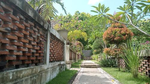 a brick wall next to a path with plants at Cersen Resort Lombok in Kuta Lombok