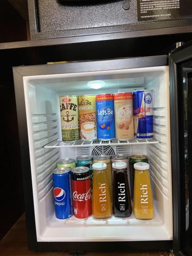 a refrigerator filled with cans and bottles of soda at City Centre Hotel in Tashkent