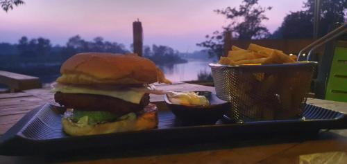 a sandwich and chips on a tray with a basket of chips at River Park Retreat in Sauraha