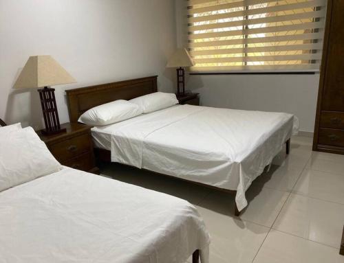 1 Schlafzimmer mit 2 Betten mit weißer Bettwäsche und einem Fenster in der Unterkunft Norjannah Homestay @Regency Tg Tuan Beach Resort in Port Dickson