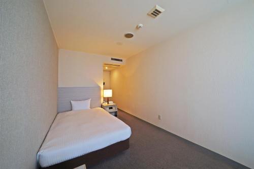 a small bedroom with a bed and a lamp at Chisun Hotel Kamata in Tokyo