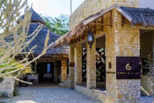 a brick building with a thatched roof at Auberge de la Table in Toliara