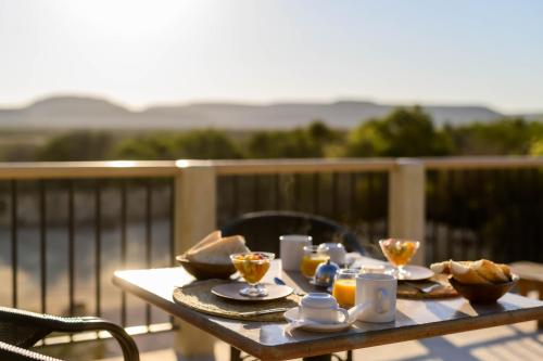 a table with cups and plates of food on a balcony at Auberge de la Table in Toliara