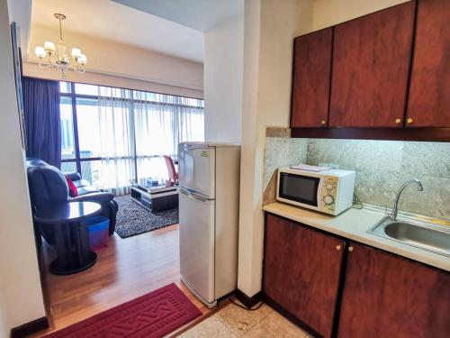 a kitchen with a refrigerator and a microwave on a counter at Times Service Suites @ Times Square in Kuala Lumpur