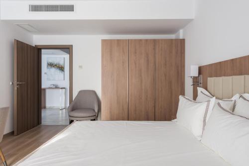 a bedroom with a large white bed and a chair at Aparthotel Pietroasa in Buzău
