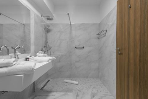 a white bathroom with a shower and a sink at Aparthotel Pietroasa in Buzău