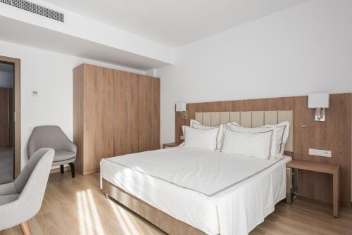 a bedroom with a white bed and a chair at Aparthotel Pietroasa in Buzău