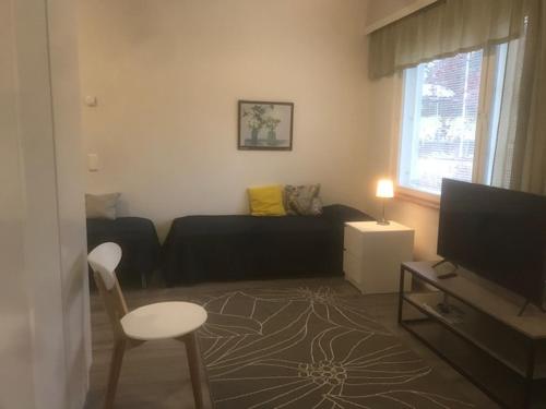 uma sala de estar com um sofá preto e uma cadeira em Muurame-City huoneet em Muurame