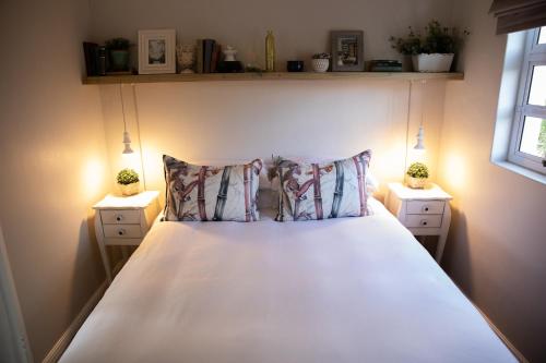 um quarto com uma cama branca com duas mesas de cabeceira em Cape Cottages em Bergvliet