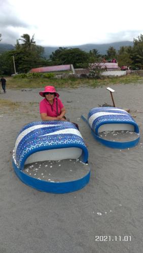 a woman sitting on the beach with two inflatables at Vineyard Guest House in Taitung City