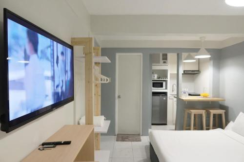 Dragonfly Apartments and Transient House في Bacoor: غرفة معيشة مع تلفزيون بشاشة مسطحة كبيرة على جدار