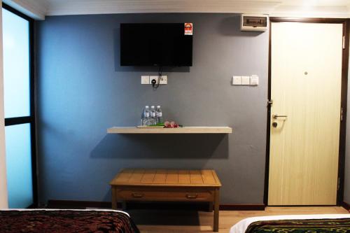 a room with a blue wall with a shelf and a tv at Kapit Hotel in Kuching