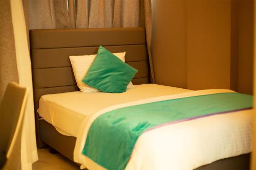 a bed with a green pillow on top of it at Dhimyaath Stay in Male City