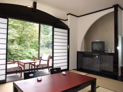 een kamer met een tafel en stoelen en een televisie bij Hotel Uguisu in Shizukuishi