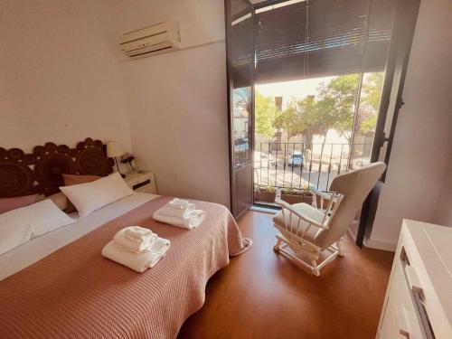 een slaapkamer met 2 bedden, een stoel en een raam bij Precioso apartamento en Plaza de las Cañas in Córdoba