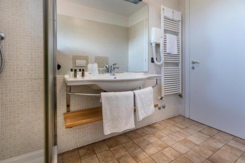 bagno con lavandino, doccia e asciugamani di APPARTAMENTI CAPRI MALCESINE a Malcesine