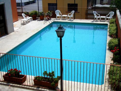 a large swimming pool with chairs and a light pole at Hotel Cervantes in Guadalajara