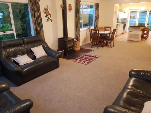 Tui Cottage في Hampden: غرفة معيشة مع أريكة جلدية وموقد خشبي