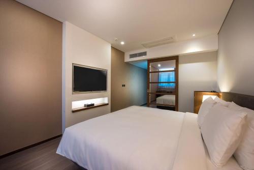 a bedroom with a white bed and a television at ENA Suite Hotel Namdaemun in Seoul
