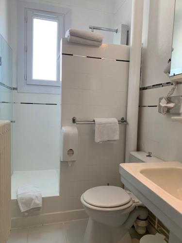 a white bathroom with a toilet and a sink at Hôtel Le Pré Catelan in Juan-les-Pins