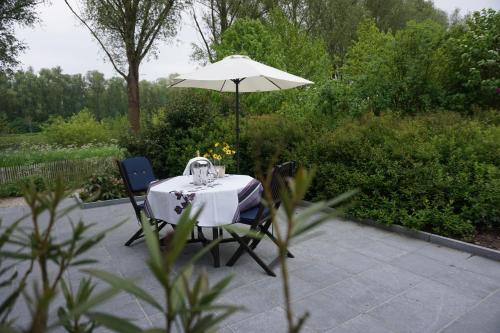 einen Tisch und zwei Stühle unter einem Schirm in der Unterkunft B&B Scheldekant in Oudenaarde