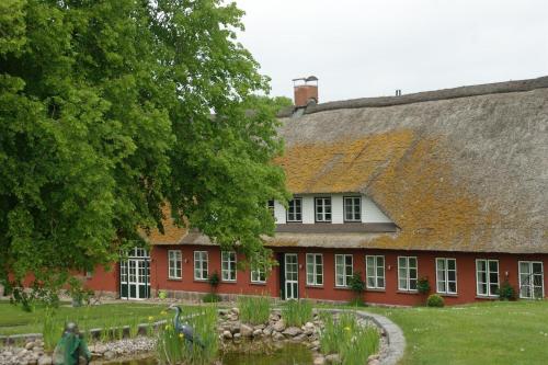 ein rotes Haus mit einem Dach und einem Garten davor in der Unterkunft Lindenhof Rüllschau in Maasbüll