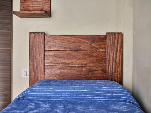 a bed with a wooden headboard in a bedroom at Circolo Operaio Acli Colloro in Alpe Lagarasc
