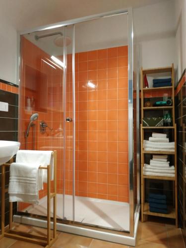 y baño con azulejos de color naranja, ducha y lavamanos. en Bed and Breakfast In Piazza Orazio, en Venosa