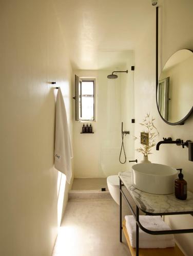 a white bathroom with a sink and a mirror at Chill & Co. Serifos in Livadi