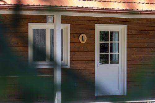 a wooden house with a white door and a window at Tusnad Camping in Băile Tuşnad